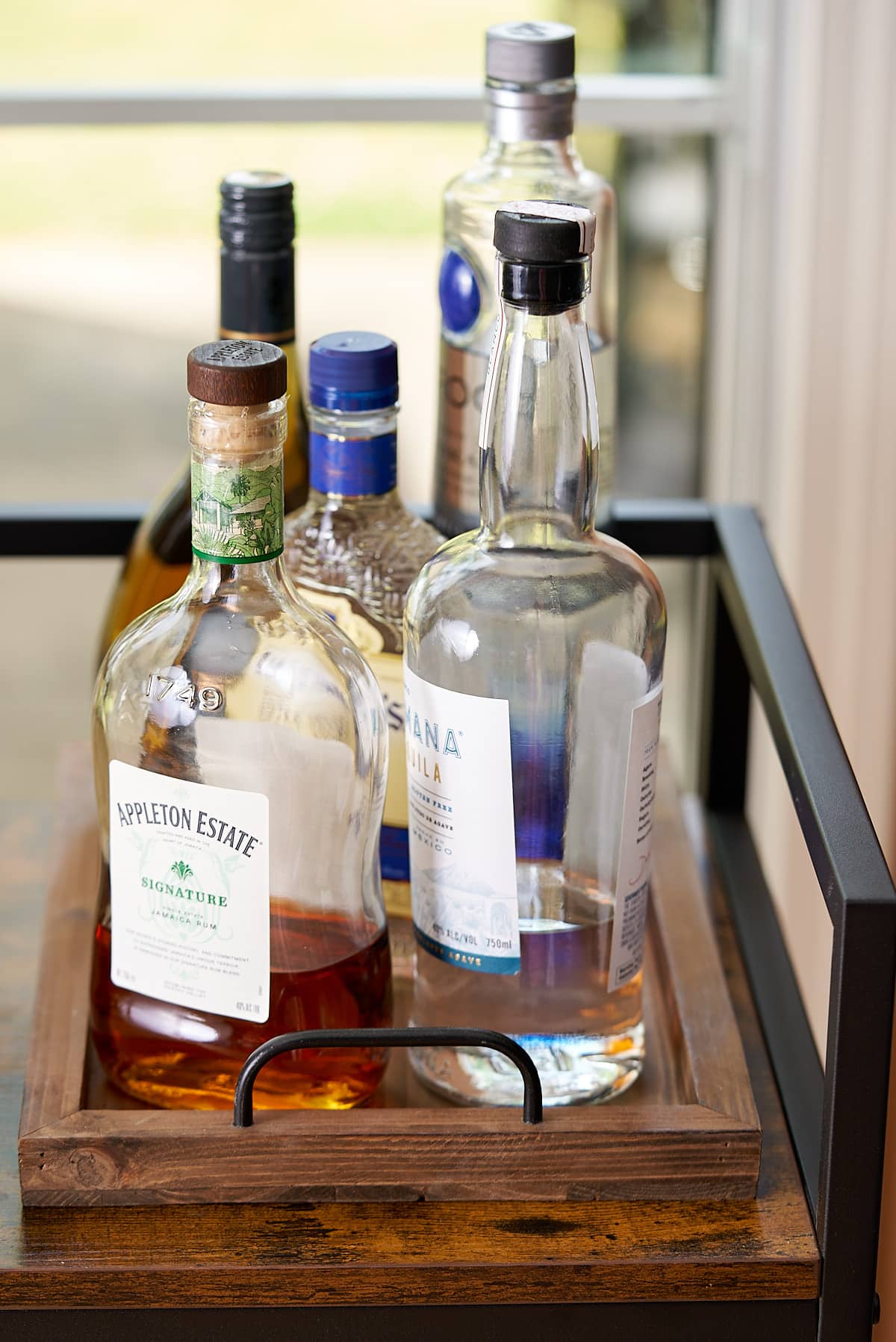 liquors in front of window on bar cart