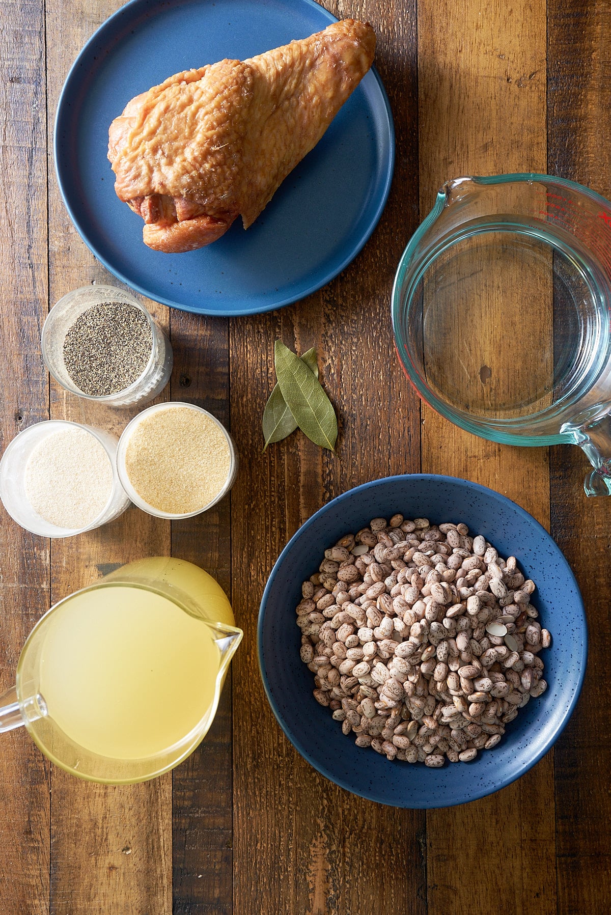 Pinto bean recipe ingredients set into individual dishes on a wooden board.