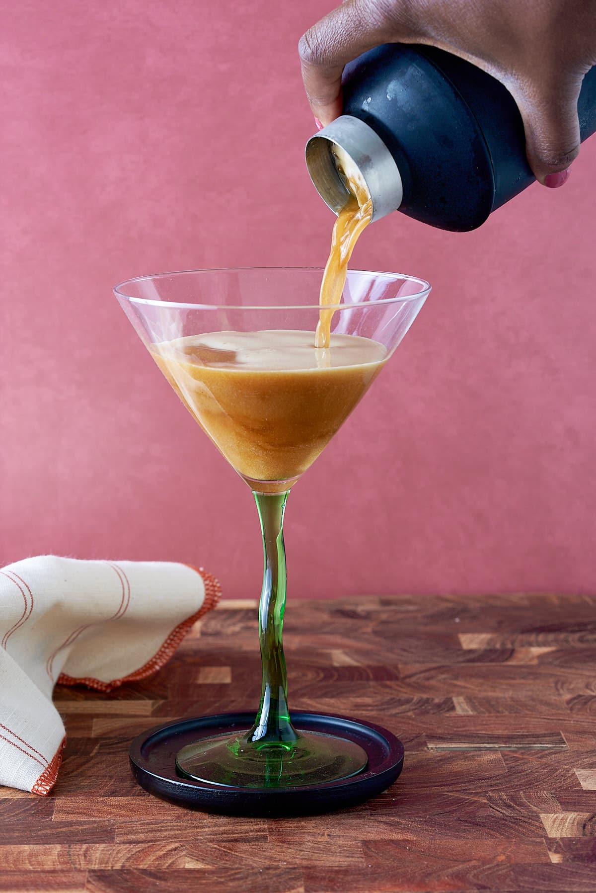 Pouring the cocktail into the martini glass.