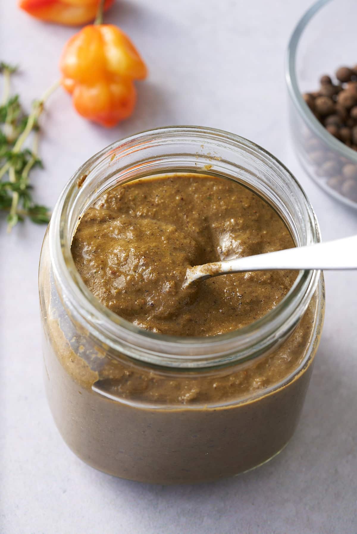 The marinade in a jar with a spoon taking some out.