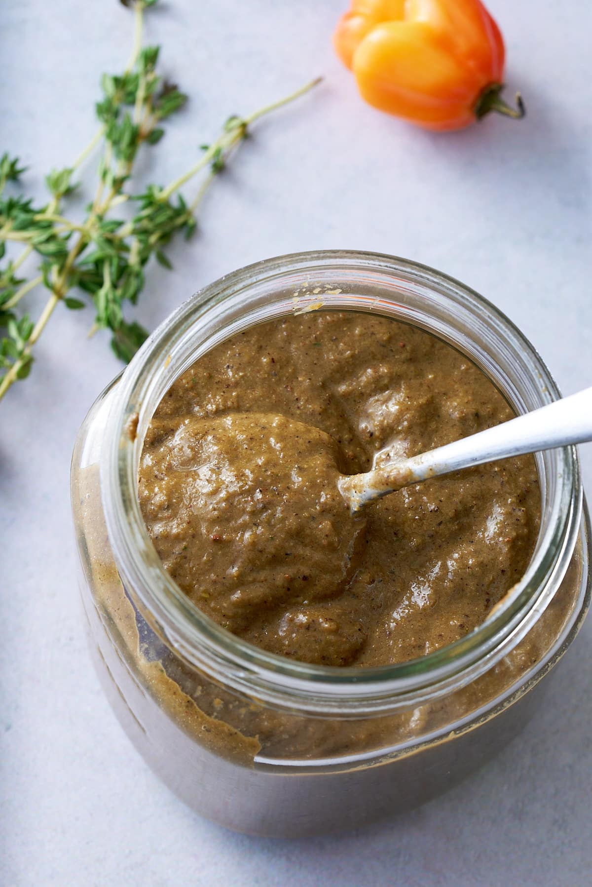 Jerk marinade in a jar with a spoon.