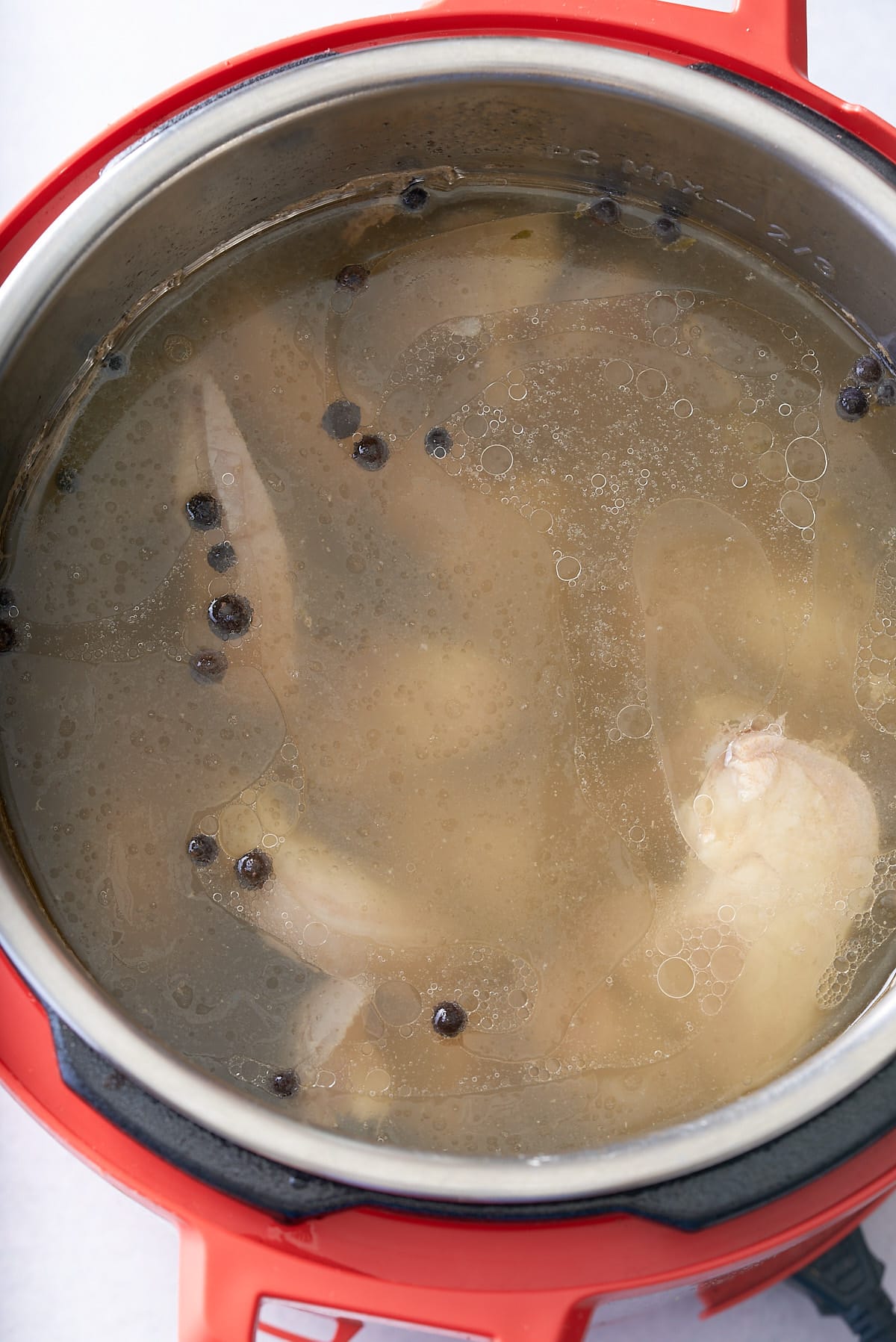 Pressure cooker bowl filled with cooked meat and a meat broth.