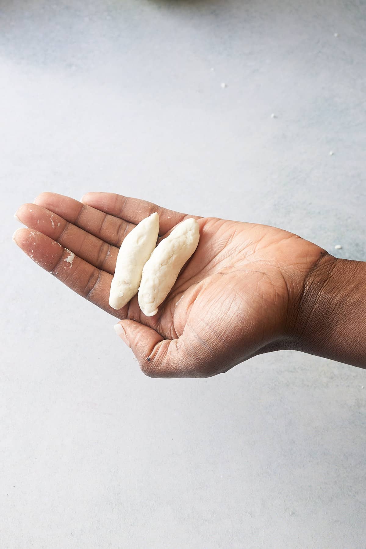 A hand holding two Jamaican spinner doughballs.