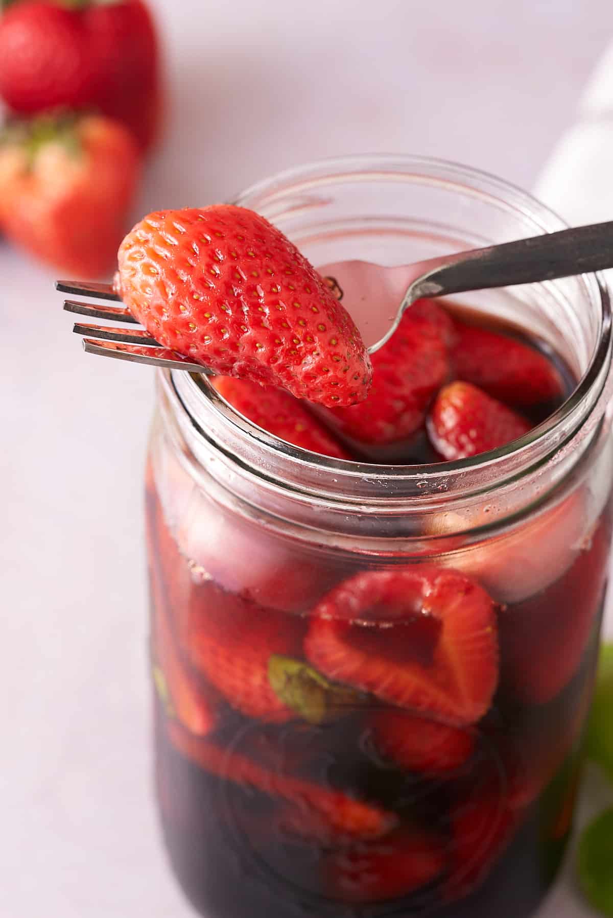 A mason jar full of fresh pickled strawberries.