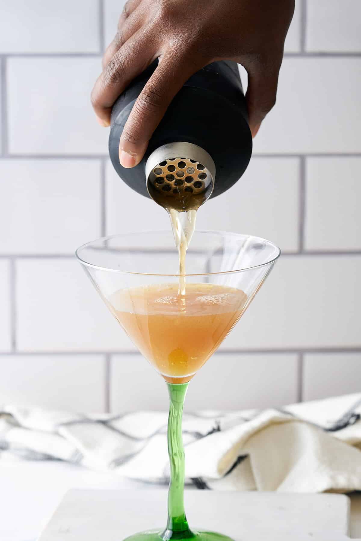 Bourbon martini being poured from a black cocktail shaker into a martini glass.