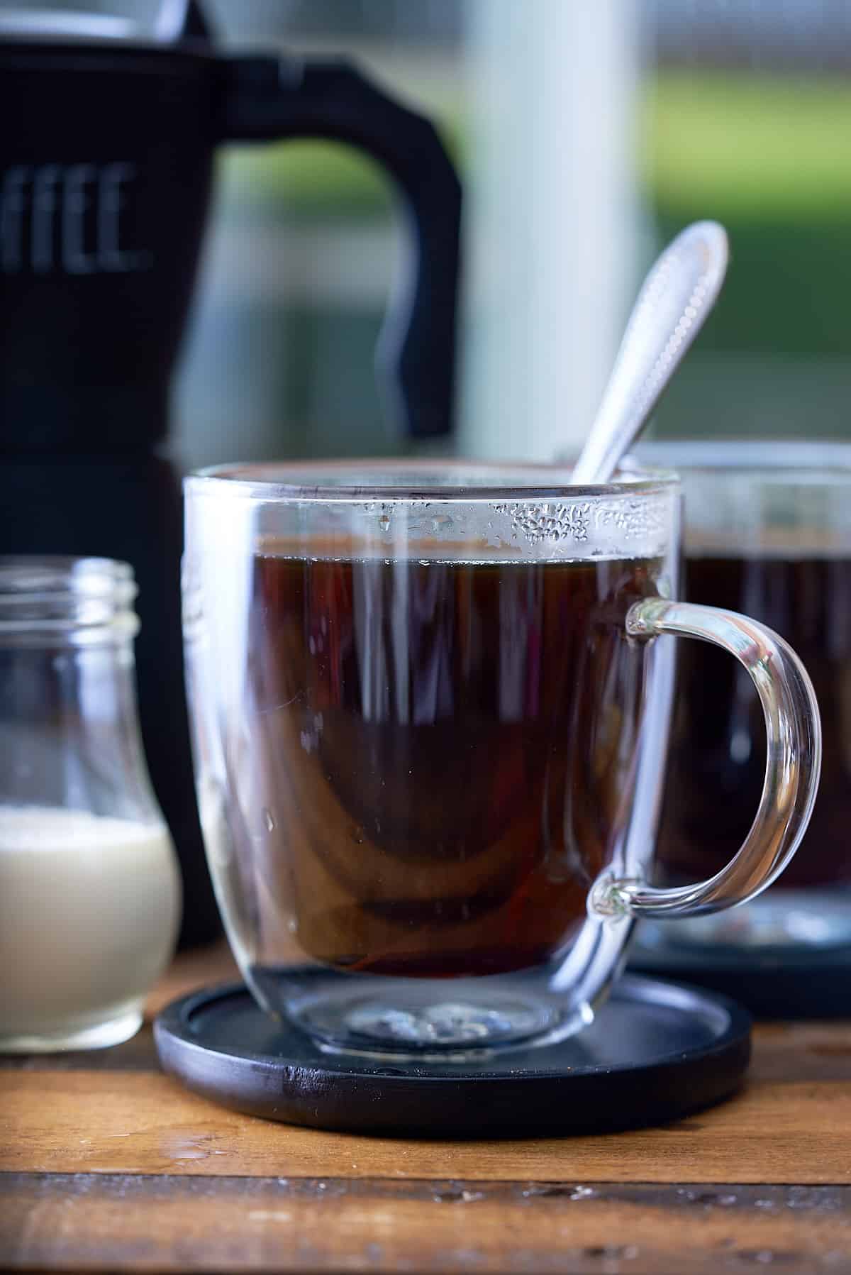 A clear glass of hot coffee.