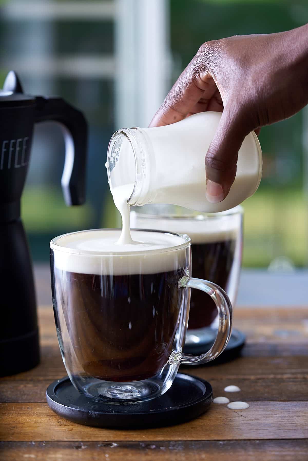 Topping the hot coffee with frothed cream.