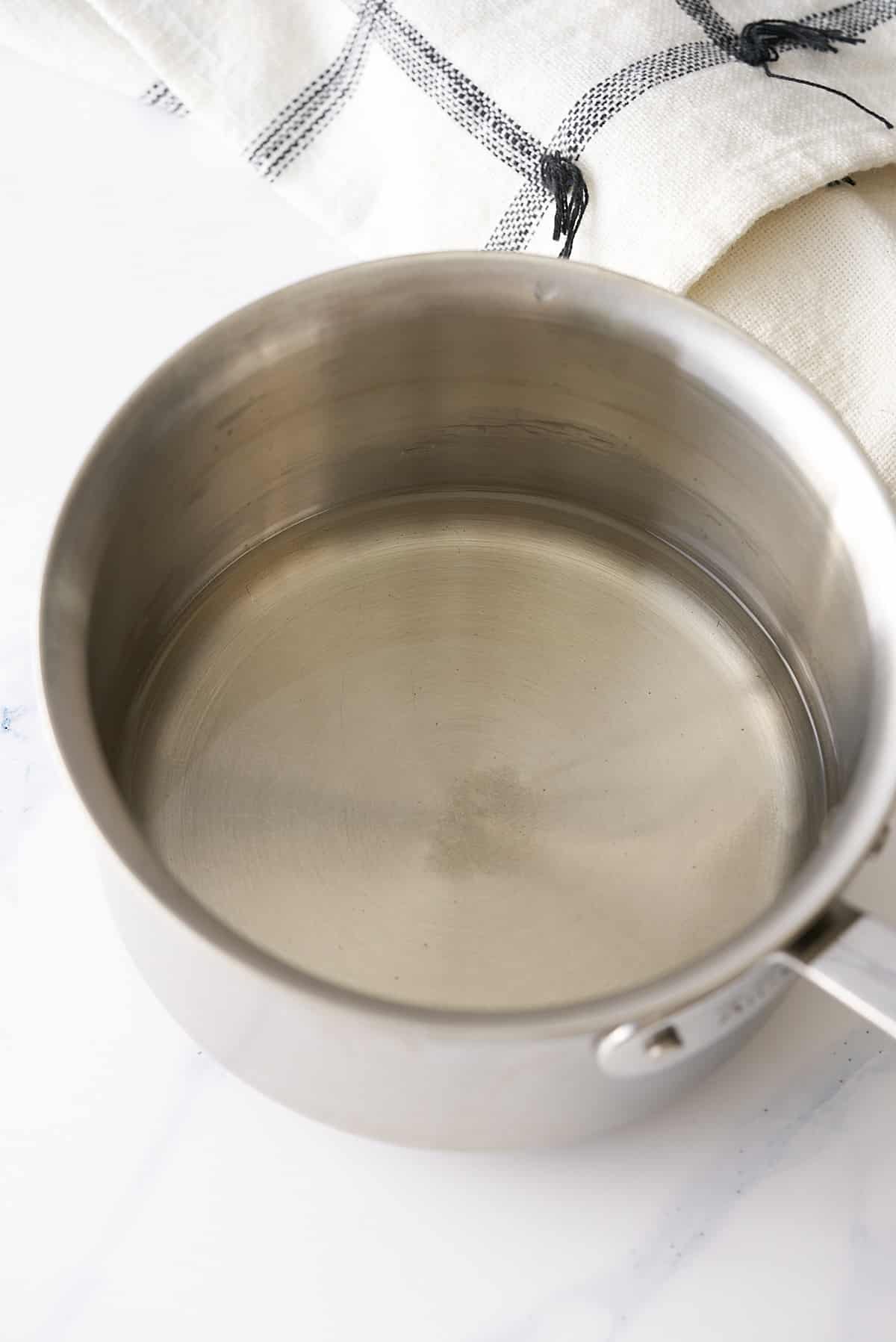 A saucepan with melted sugar and water.