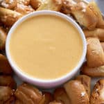 beer cheese dip in white bowl with pretzels surrounding it