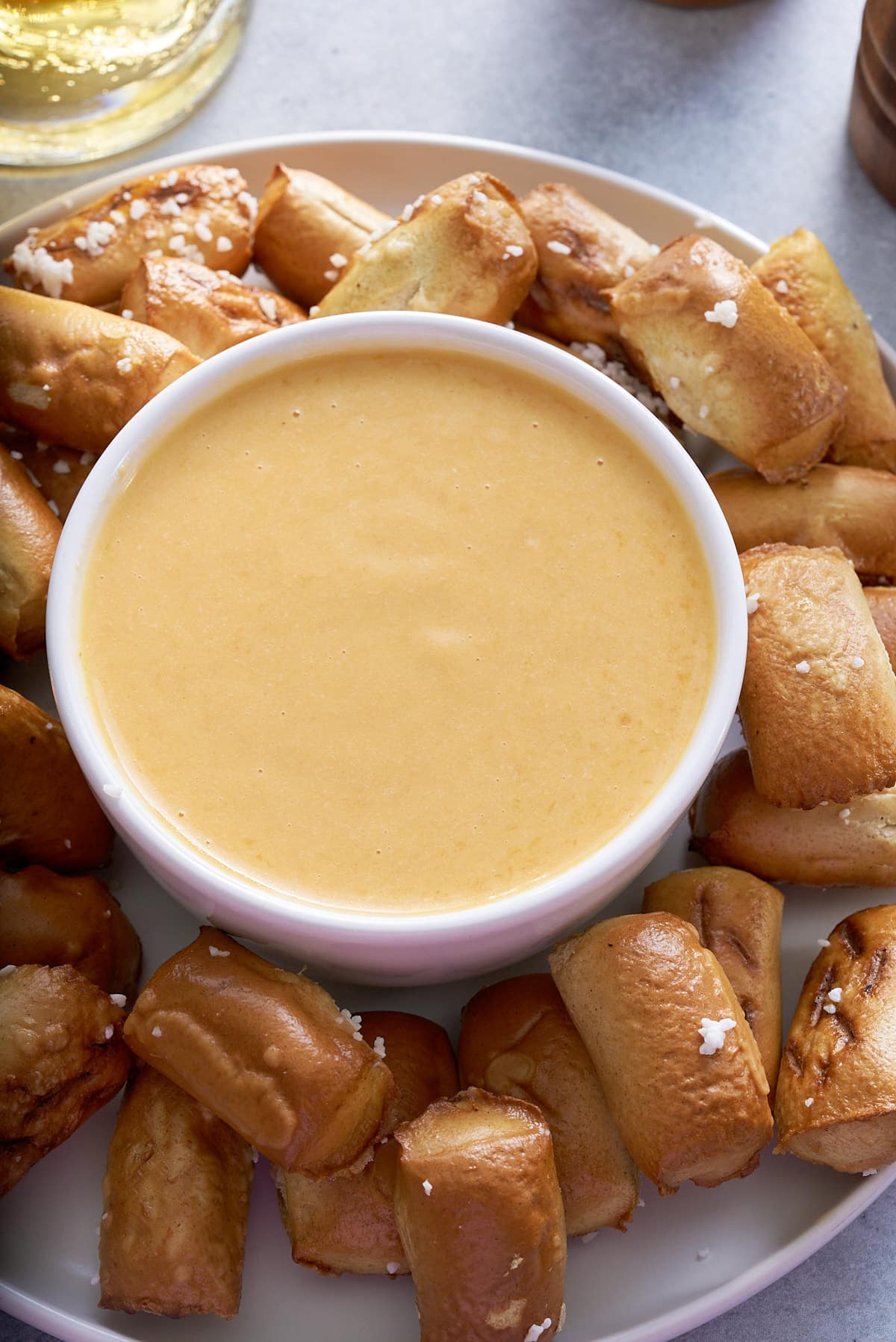 beer cheese dip in white bowl with pretzels surrounding it