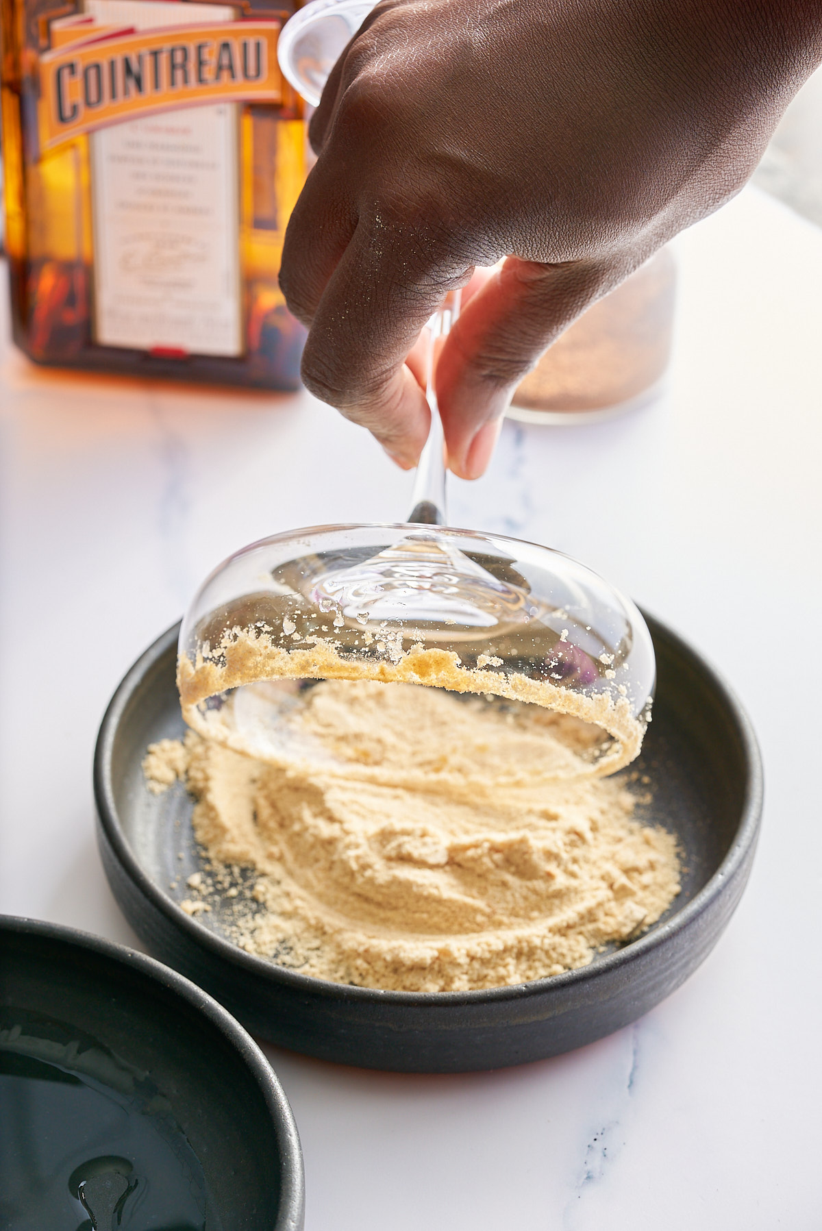 A cocktail class being coated in Graham cracker sugar around the rim.