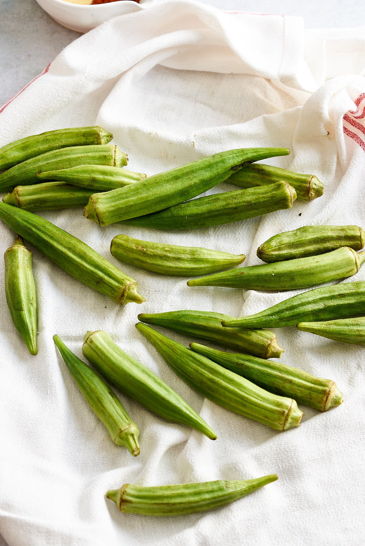 Whole okra being dried on a kitchen towel.