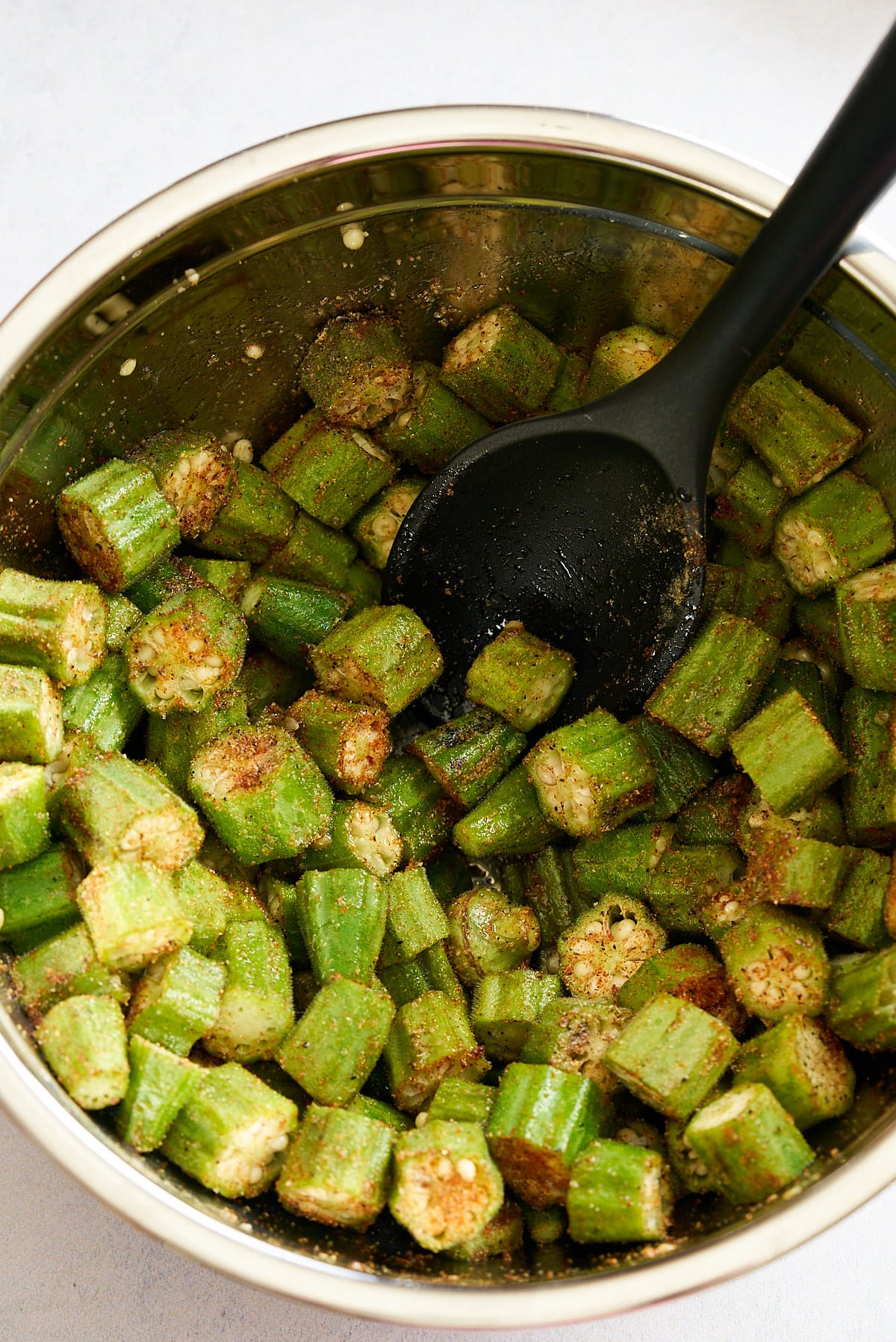 A silver bowl filled with sliced okra, covered in a blend of salt and spices.