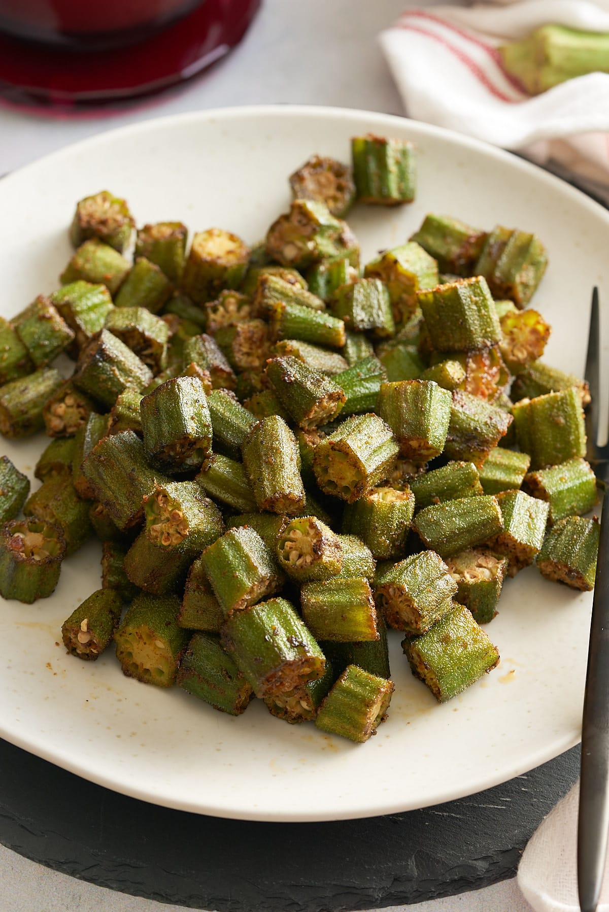 A white serving platter with roasted okra.