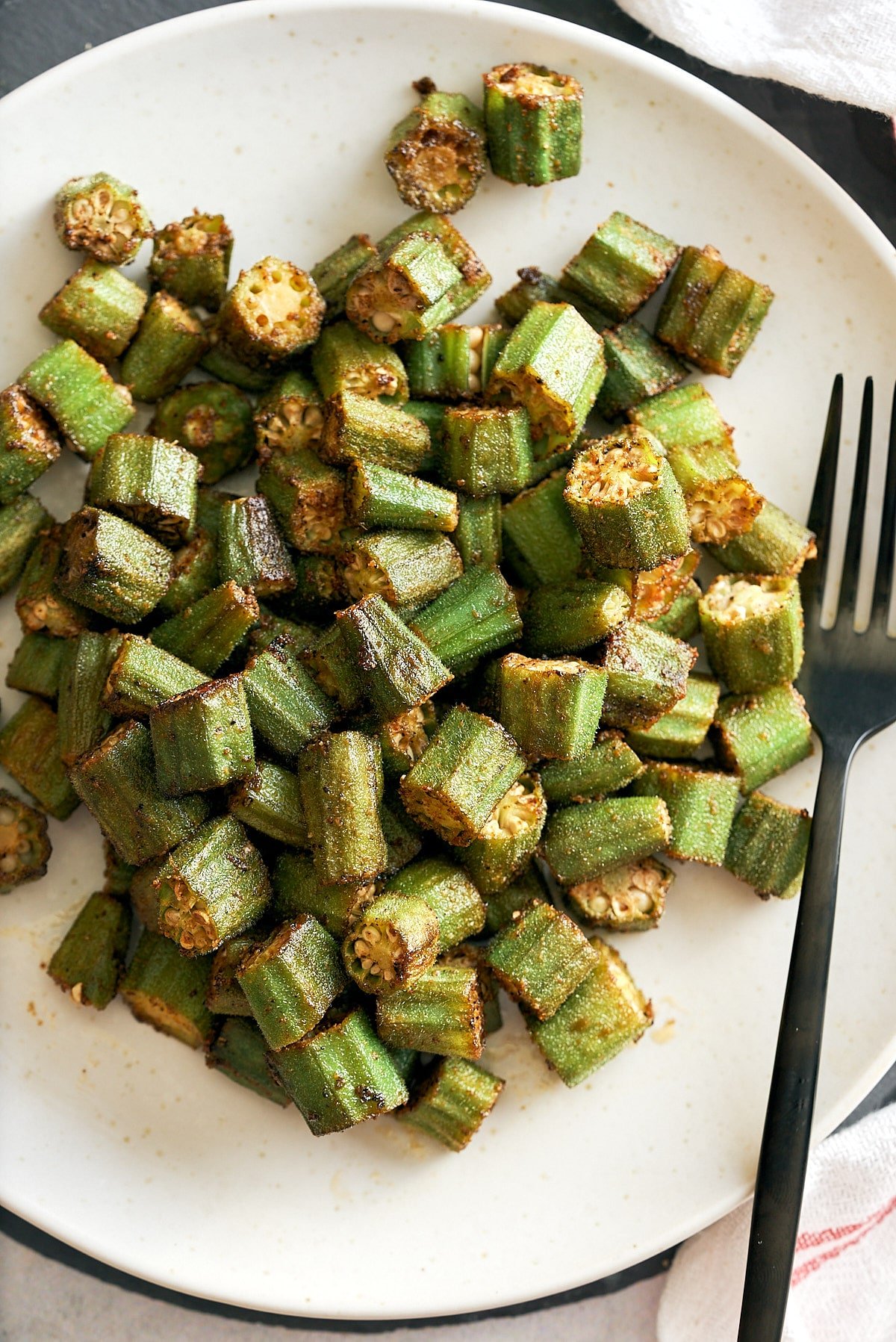 A white serving platter with roasted okra.