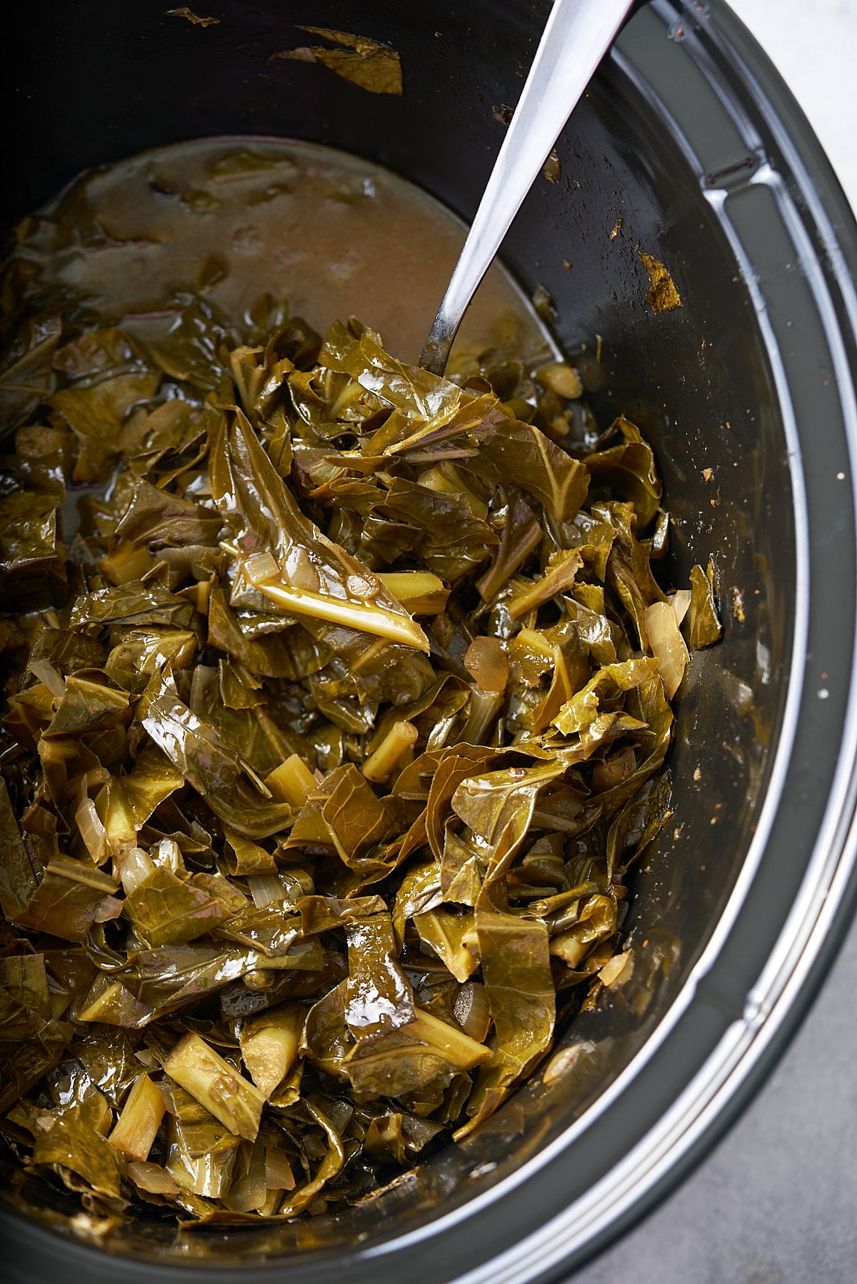 collard greens in slow cooker with spoon sticking out