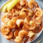 steamed shrimp in white bowl with lemon on side