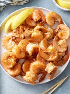 steamed shrimp in white bowl with lemon on side