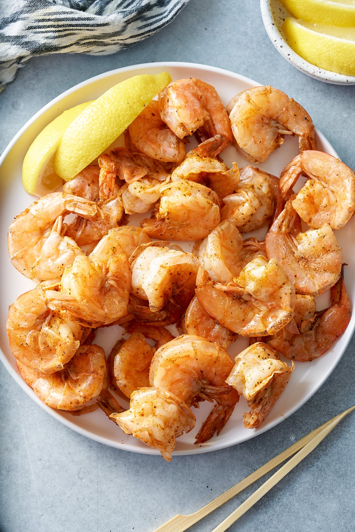 steamed shrimp in white bowl with lemon on side