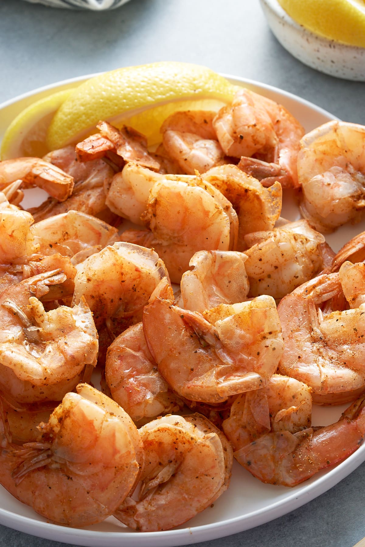 steamed shrimp in white plate with lemon in back