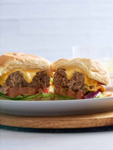 A prepared steamed cheeseburger cut in half.