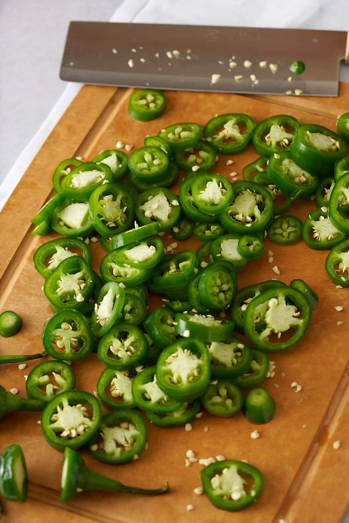 Fresh jalapenos cut into slices on a cutting board.