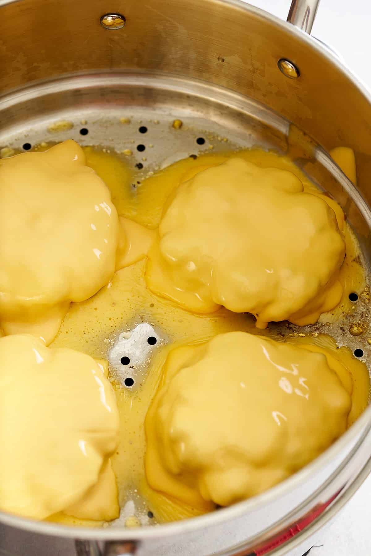 Cheese placed on top of the steamed burgers and melted.