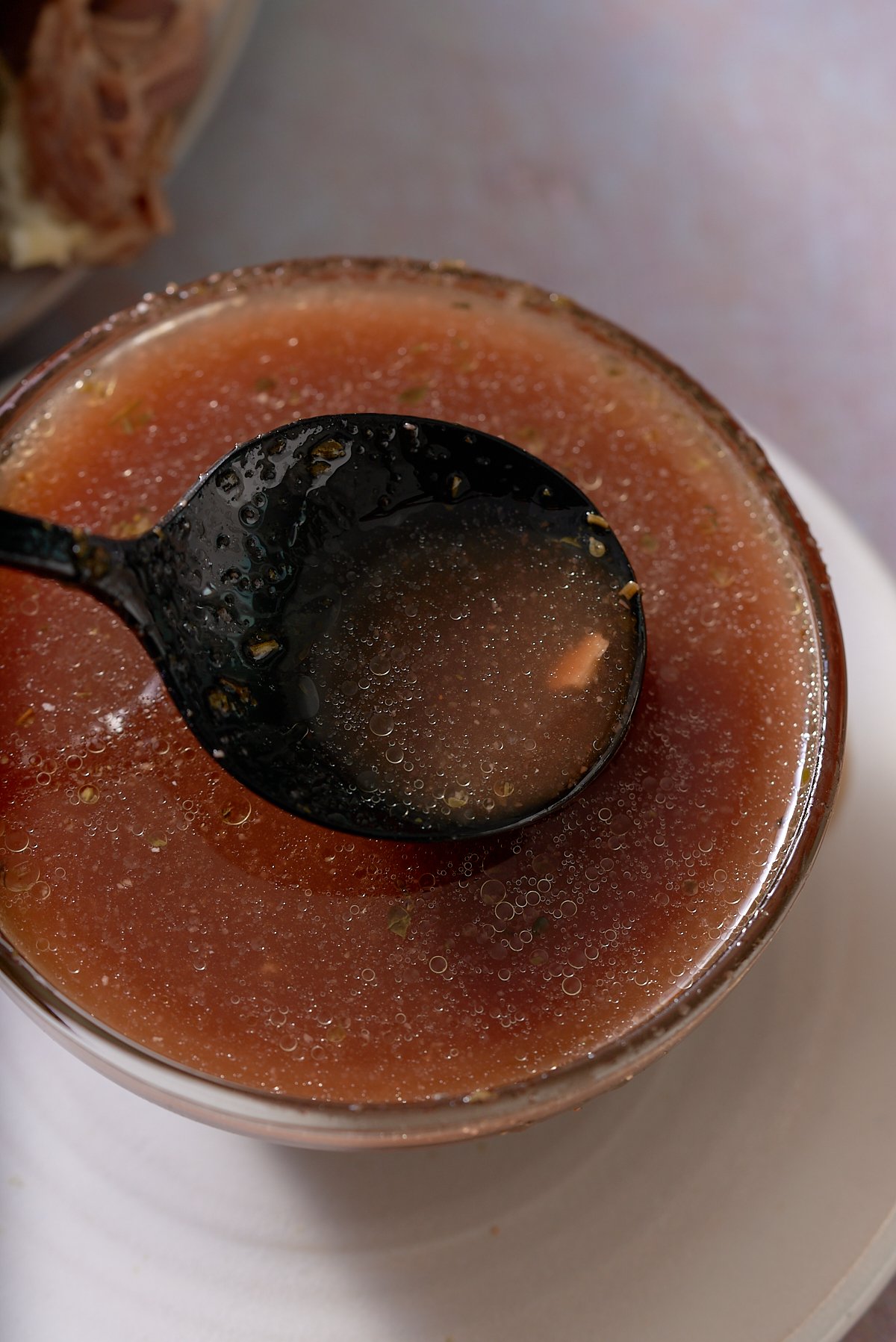 A glass bowl filled with au jus.