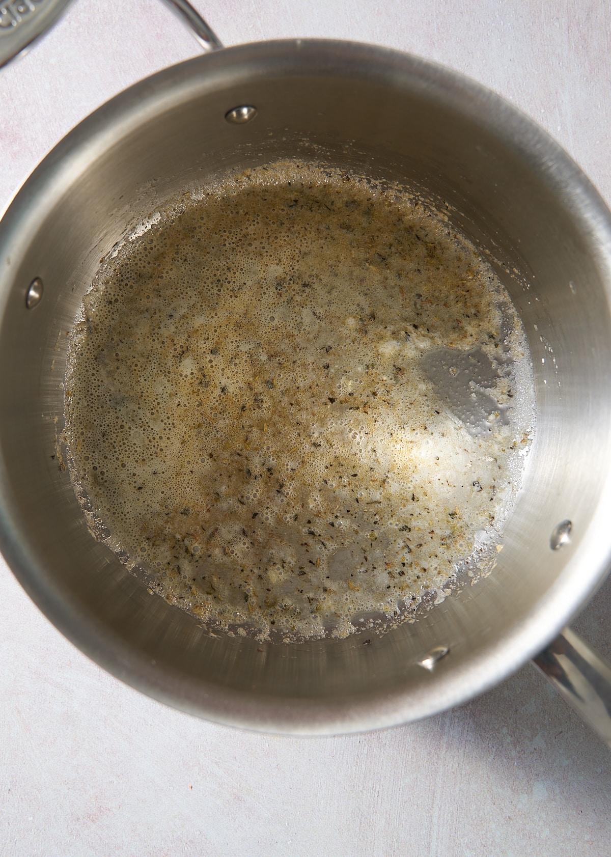 A small saucepan with melted butter and seasoning.