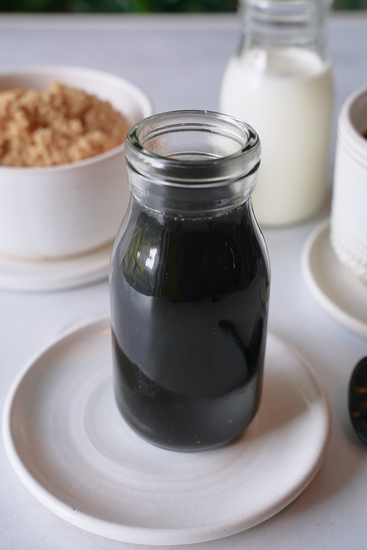 Brown sugar syrup in a glass jar sat on a white plate.