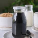 Brown sugar syrup in a glass jar sat on a white plate.