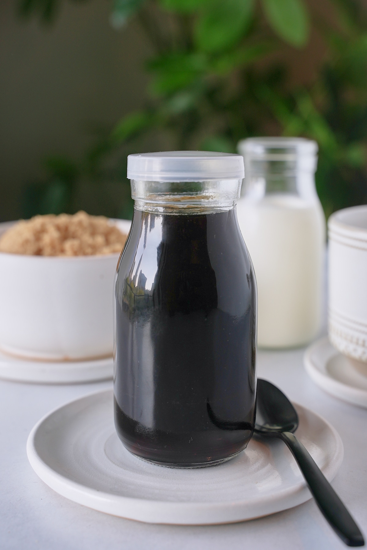 Brown sugar syrup in a glass jar sat on a white plate.