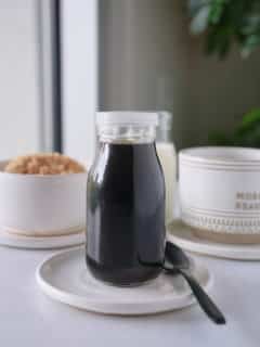 Brown sugar syrup in a glass jar sat on a white plate.