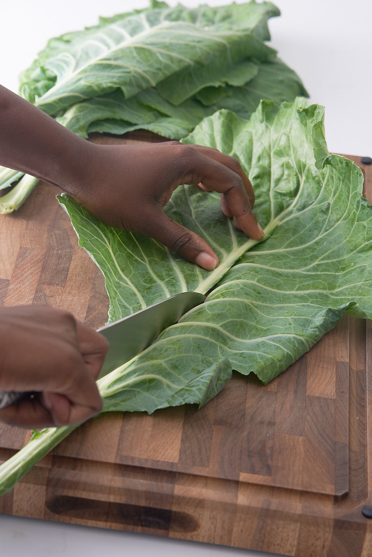 hand removing stem from collard green with knife