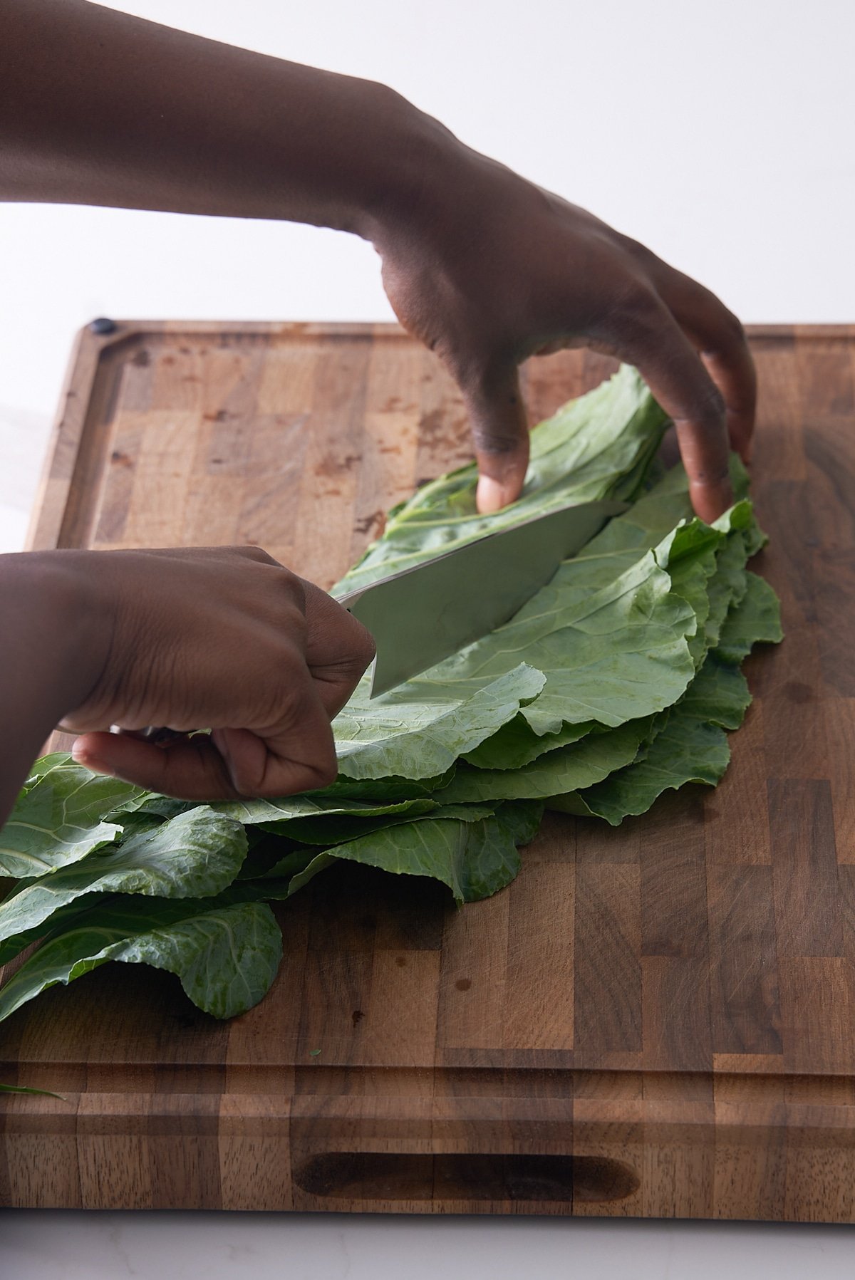 collard green folded in half and knife cutting down half of collard green