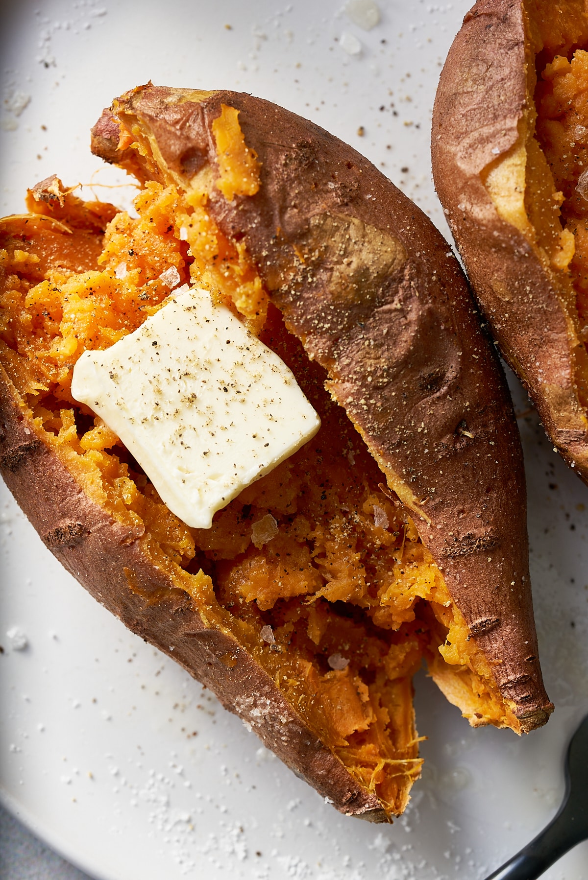 A cut open sweet potato with a pat of butter on it.