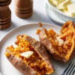 Two sweet potatoes cut open on a white plate.