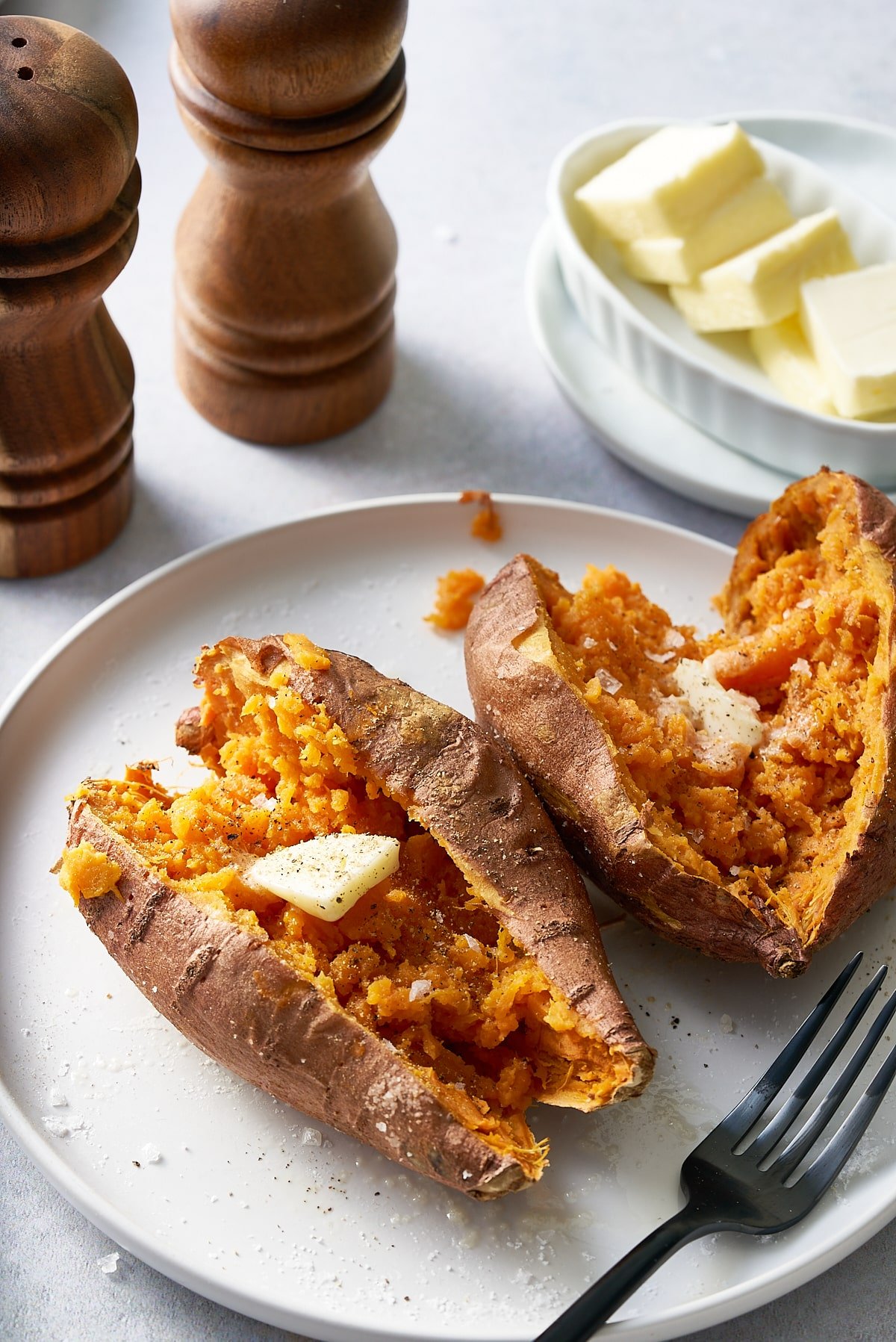 Two sweet potatoes cut open on a white plate.