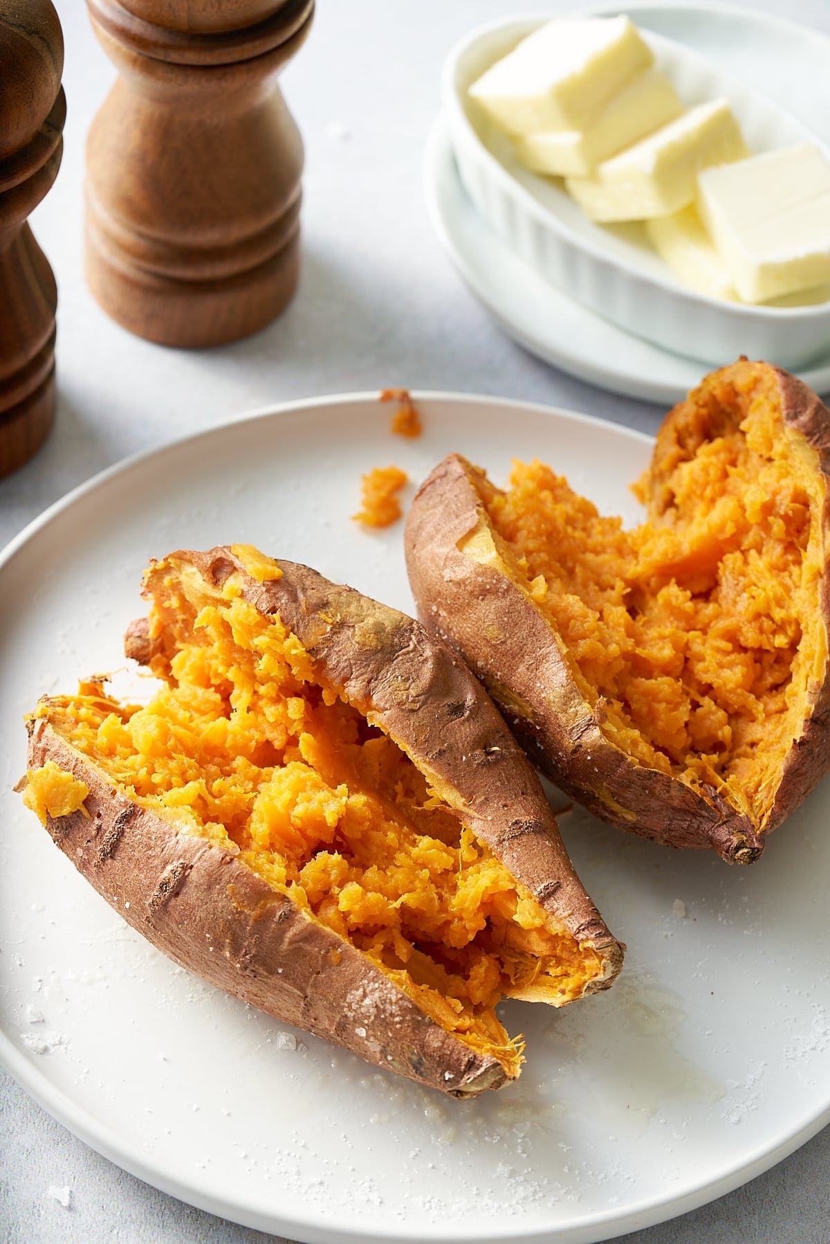 Two sweet potatoes cut open on a white plate.