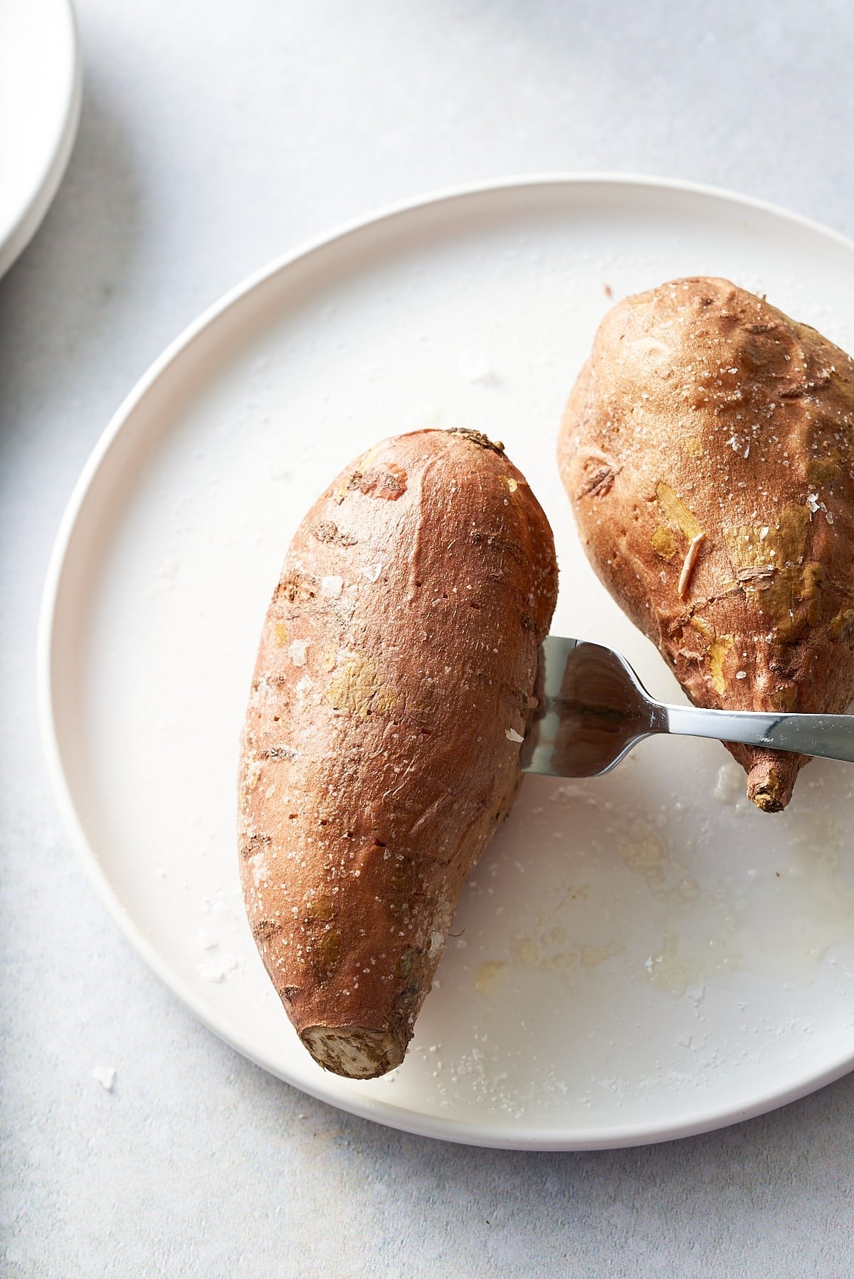 Testing the doneness of a sweet potato with a fork.