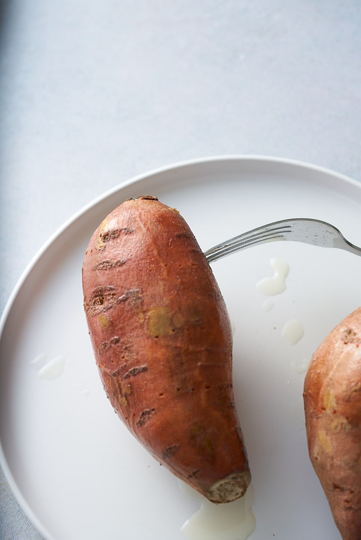 Testing the doneness of a sweet potato with a fork.