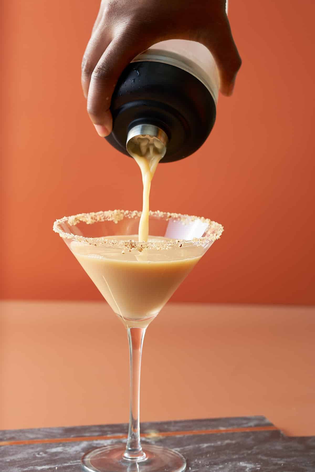 Pouring the mixed cocktail into the martini glass.