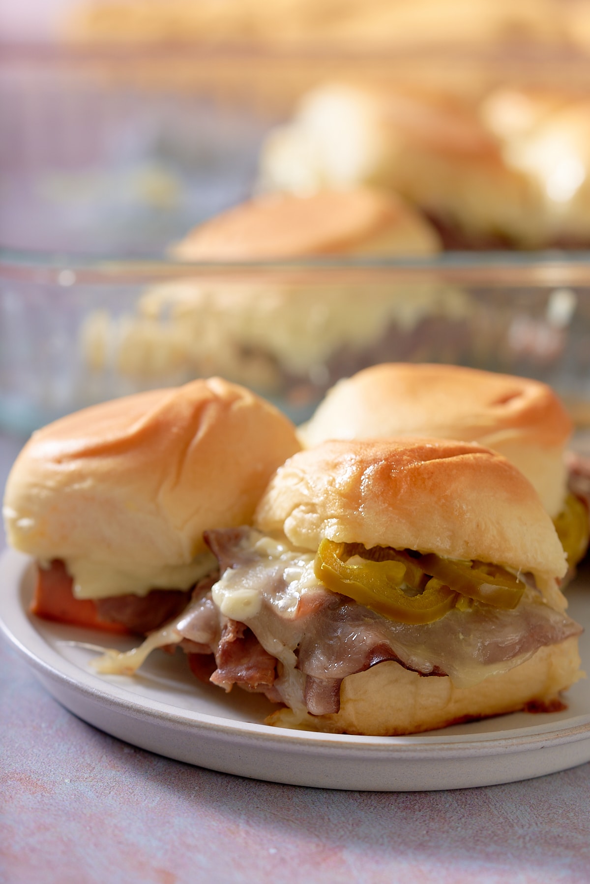 Close up of 3 toasted roast beef sliders on a white plate.