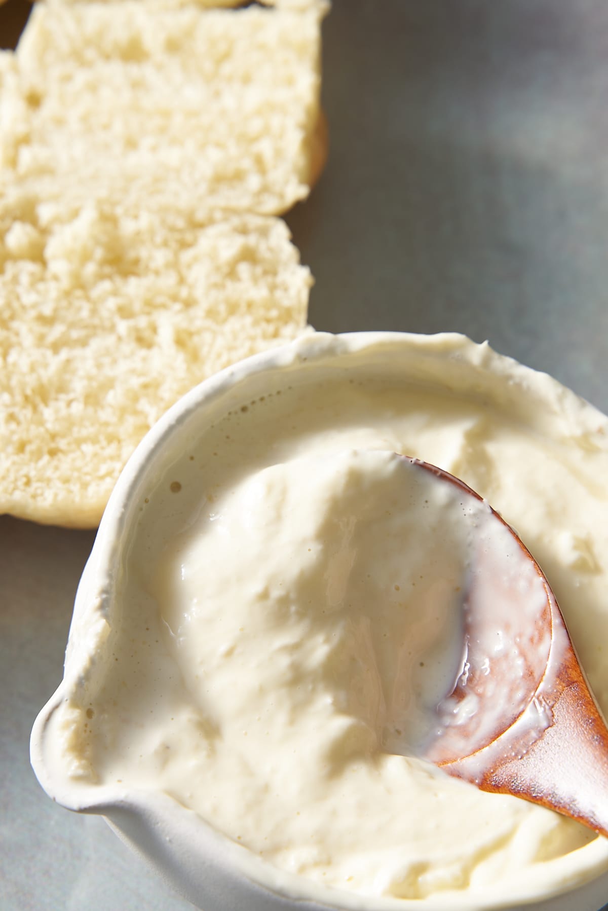 A small bowl with a combination of mayonnaise and prepared horseradish being mixed with a wooden spoon.