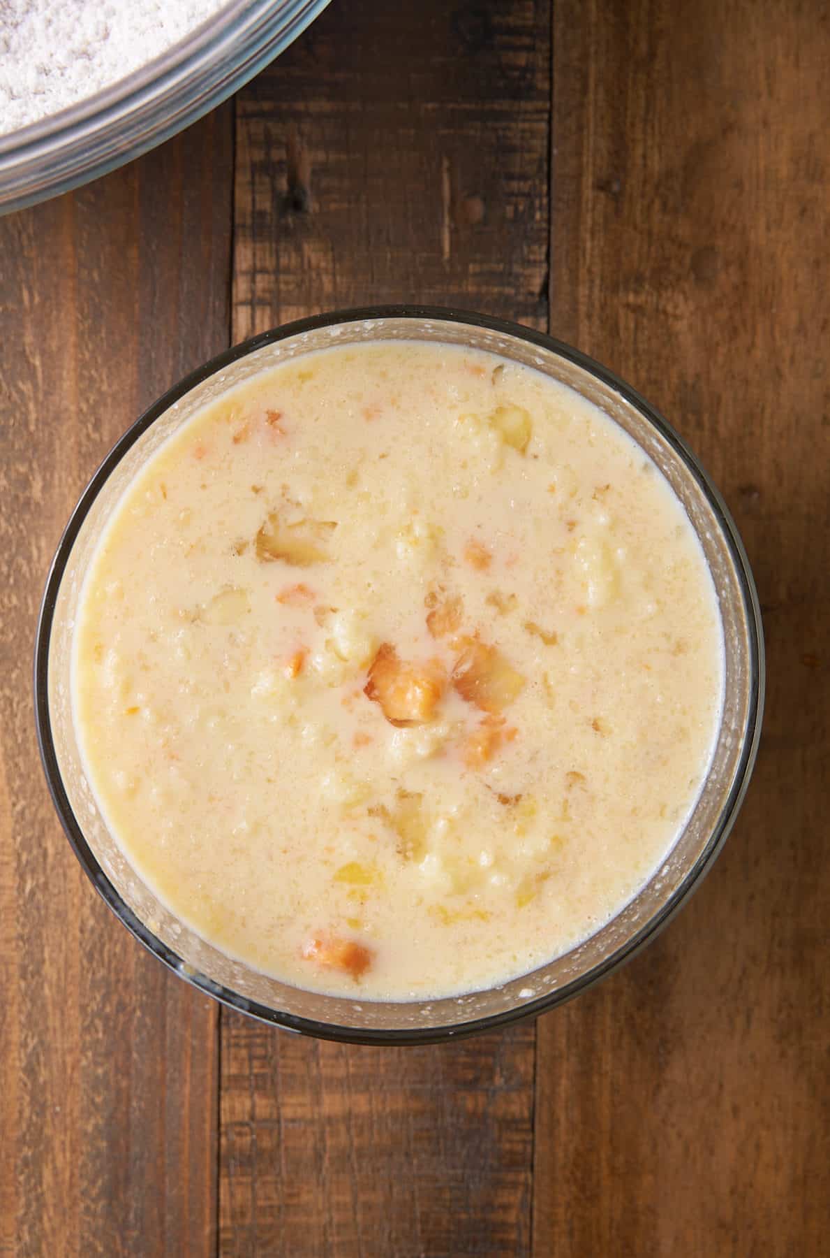 A glass bowl filled with milk, eggs, sweet potato, melted butter, brown sugar and vanilla extract.