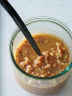 A glass jar filled with warm bacon vinaigrette.