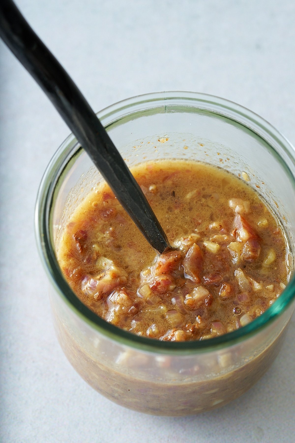 A glass jar filled with warm bacon vinaigrette.