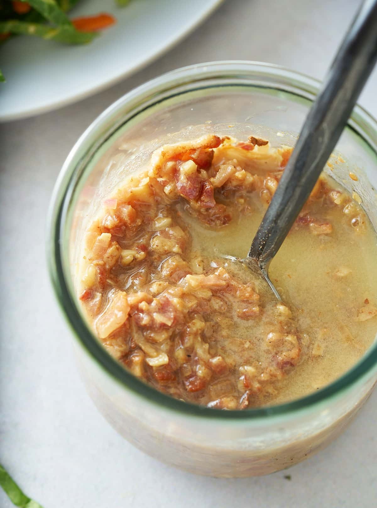 A glass jar filled with warm bacon vinaigrette.