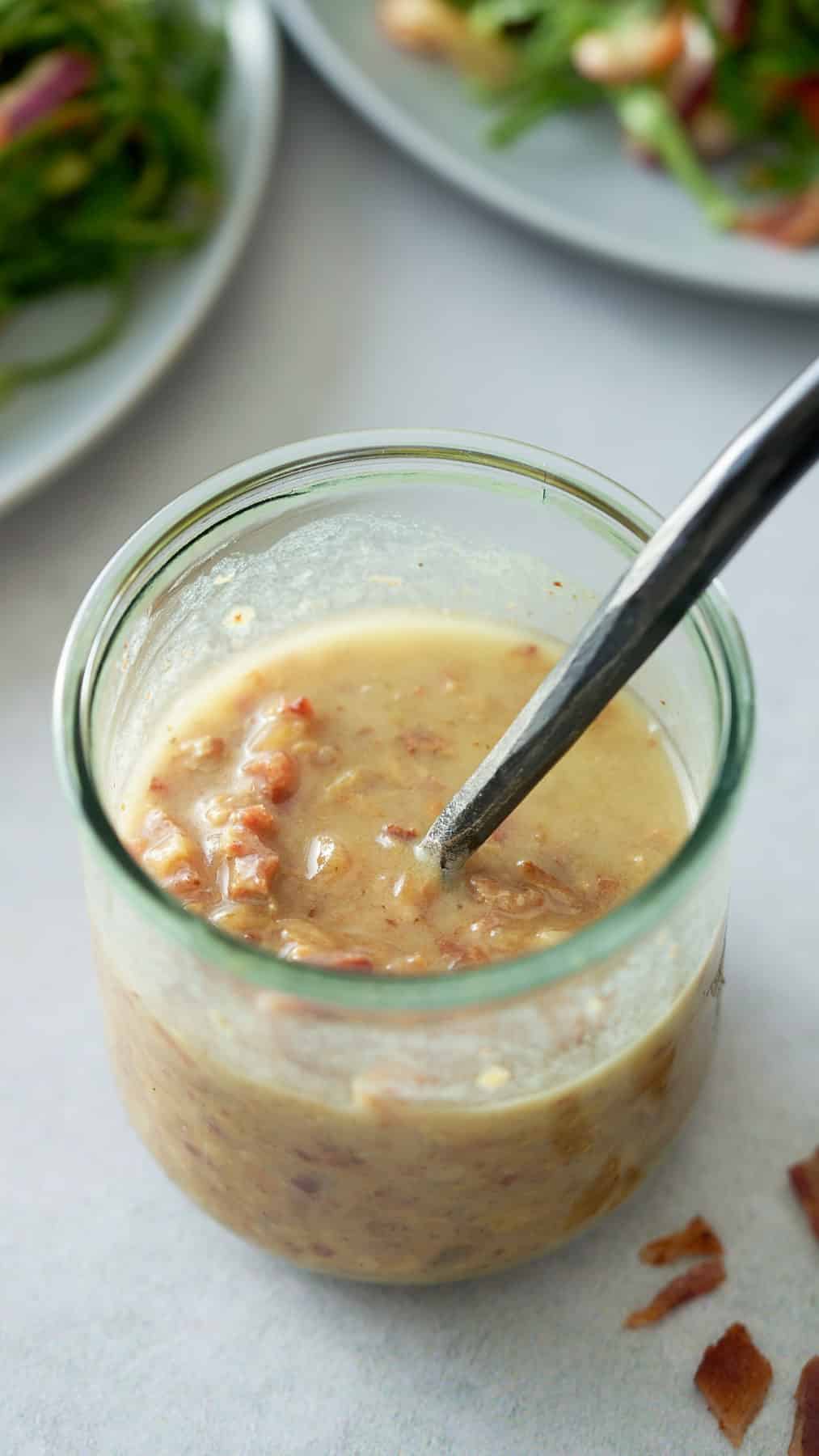 A glass jar filled with warm bacon vinaigrette.