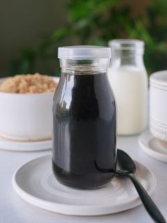 Brown sugar syrup in a glass jar sat on a white plate.